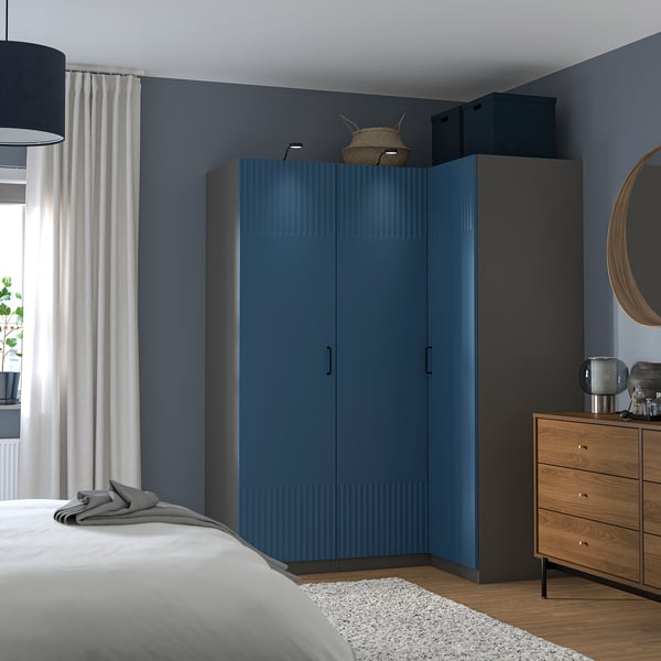 Modernes Schlafzimmer mit blauem PAX-Kleiderschrank, Kommode und Bett.