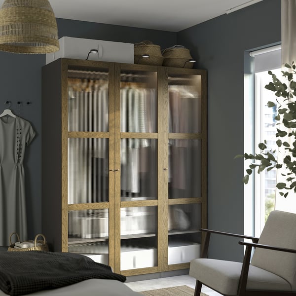 Großer IKEA PAX-Kleiderschrank aus Holz mit Glastüren, hoch und modern, passt gut zwischen Fenster und Kleidung.