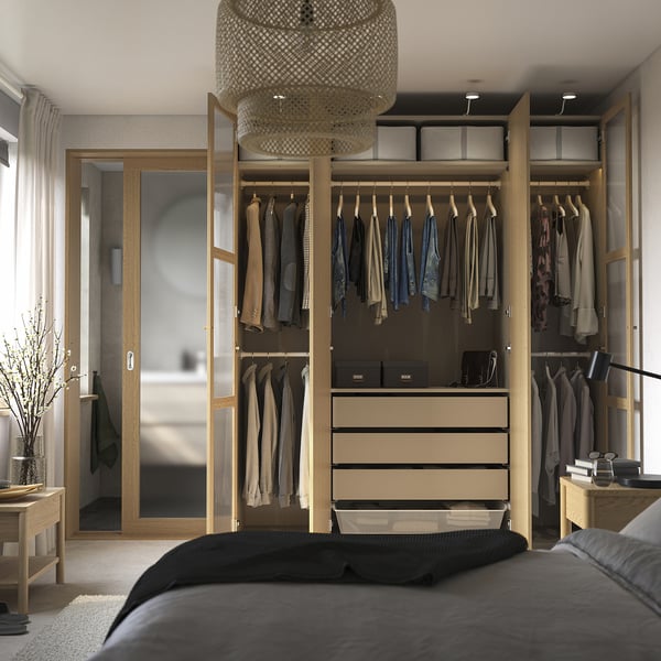 Schlafzimmer mit modernem offenem Kleiderschrank mit Kleidung, Schubladen und Regalen. Leuchte und angeschlossener Raum sichtbar.