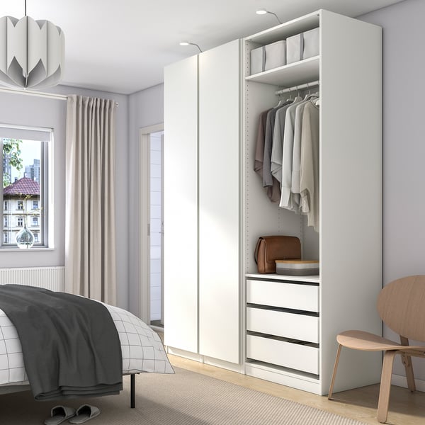 Minimalistisches Schlafzimmer mit weißem PAX-Kleiderschrank, Bett und Fenster mit Lichtvorhängen.