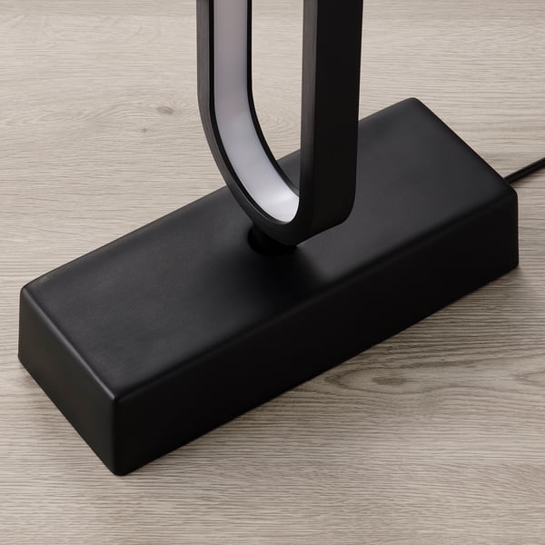 Moderne schwarze Stehleuchte mit gebogener LED, auf Holz.