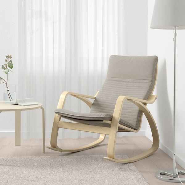 Der minimalistische Schaukelstuhl mit gepolsterten Kissen steht am Fenster und bietet Komfort und Halt.