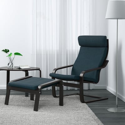 Gemütlicher blauer POÄNG Sessel mit Fußhocker & Beistelltisch, Stehleuchte, Pflanze, neutraler Raum.