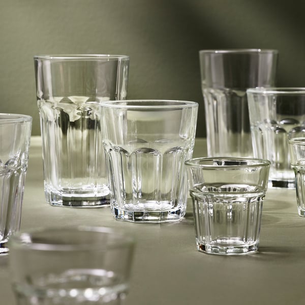 Set von Klarglasbechern in verschiedenen Größen, mit geriffelter Textur, ordentlich angeordnet auf einer grünen Oberfläche.