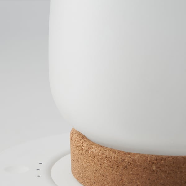 Nahaufnahme einer schlanken, modernen Leuchte mit glatter Glaskuppel und strukturiertem Korksockel, die hochwertige Materialien und Design präsentiert.