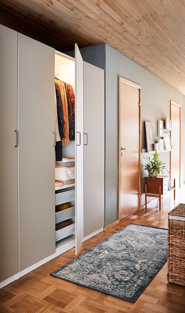 Offener Kleiderschrank mit organisierter Kleidung und Regalen im Flur, der modernes Design mit Holzvertäfelung und blauem Teppich präsentiert.