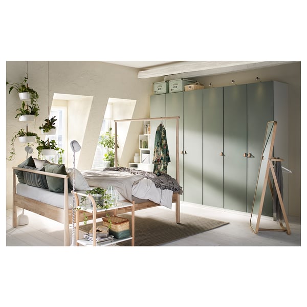 Modernes Schlafzimmer mit hellem Holzbett, grünen Regalen, Hängepflanzen und grünem Kleiderschrank mit sanft schließenden Scharnieren.