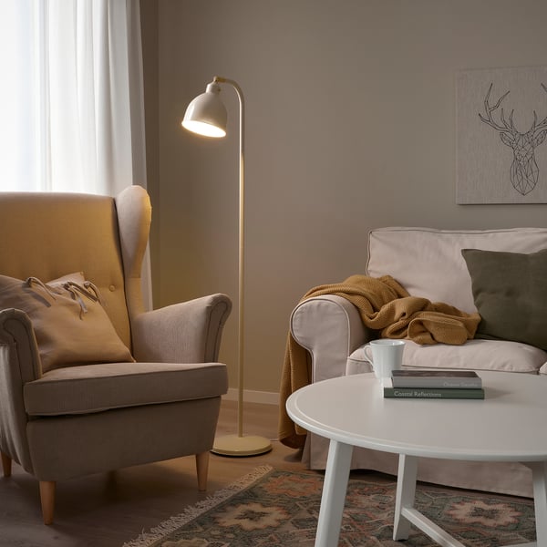 Gemütliches Wohnzimmer mit RÖDFLIK-Lampe, grauem Sessel und grünem Kissensofa.