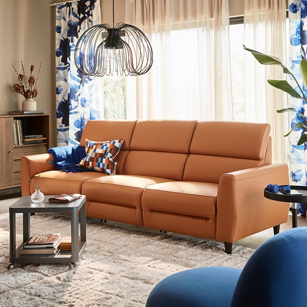 Orangefarbenes RULLERUM-Sofa im Wohnzimmer, hohe Rückenlehne, blaue Akzente, Fokuspunkt.
