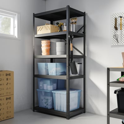 Schwarzes RYKTA Organizer-Regal mit großen blauen Plastikbehältern unten, weißen und orangefarbenen Behältern in der Mitte und Werkzeugen oben. Verschiedene Gegenstände liegen herum.