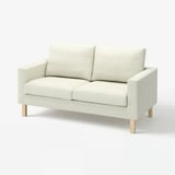 Ein beiges SALTSJÖBADEN-Zweisitzer mit Holzbeinen, das ein minimalistisches und modernes Design aufweist.