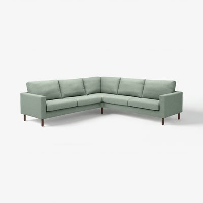 Das Bild zeigt ein grünes, l-förmiges SALTSJÖBADEN-Ecksofa mit Holzbeinen, das ein schlichtes und sauberes Design aufweist.
