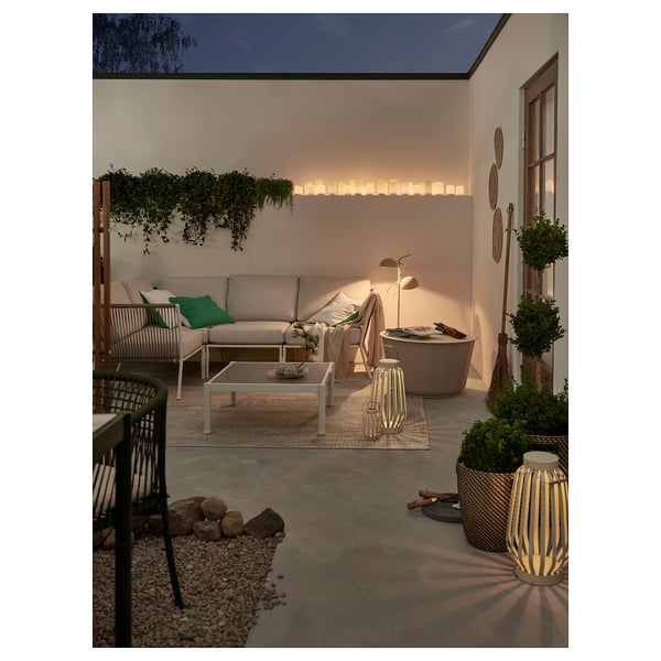 Gemütliche Terrasse mit beigen SEGERÖN-Möbeln, Teppichen, Laternen und Pflanzen.