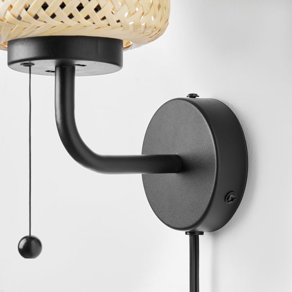 Handgefertigte Wandleuchte aus Bambus mit klarem Design, montiert auf mattschwarzem Sockel und verstellbarem Arm. Gut gemachte, stilvolle Wohnkultur.