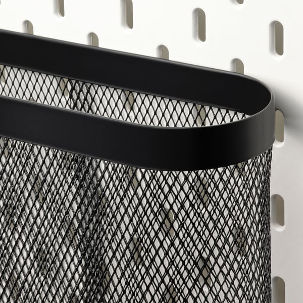 Schwarzer Organizer aus Metallgitter mit abgerundeter Oberseite, der mit Haken an einer Wand befestigt ist. Robuste und stilvolle Aufbewahrungslösung.