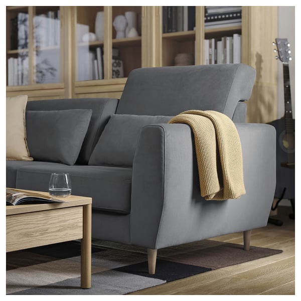 Modernes graues SLATORP-Sofa mit Holzbeinen, kuscheligen Decken und Weinglas auf einem Couchtisch.