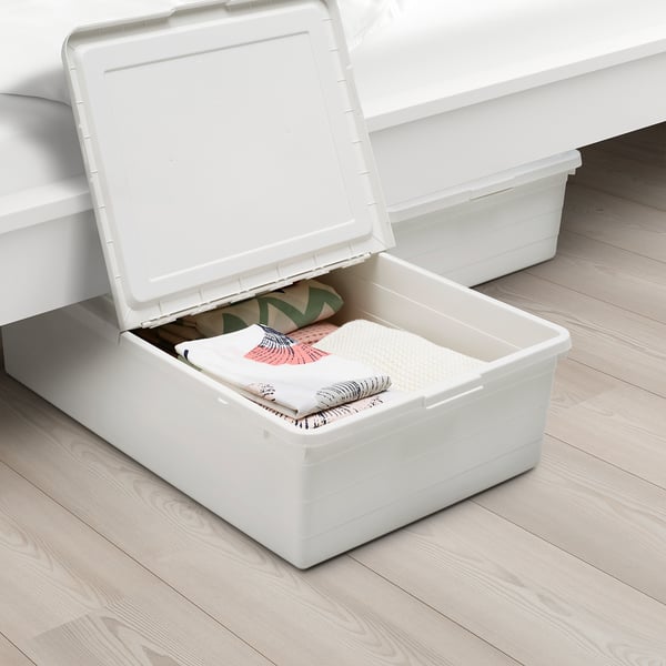 Zwei weiße Aufbewahrungsboxen unter einem Bett. Eine Schachtel ist geöffnet und gibt den Blick auf ordentlich gefaltete Kleidungsstücke frei. Der Deckel verfügt über eine Verriegelungsfunktion und ermöglicht eine Luftzirkulation.