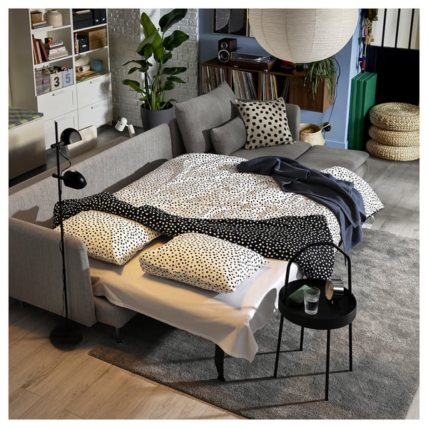 Modernes Wohnzimmer mit grauem Schlafsofa von SÖDERHAMN , schwarz-weißer Polka-Dot-Bettwäsche, schwarzem Beistelltisch und Hängelampen, gemütlich und stilvoll.