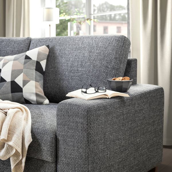 Graues Sofa mit offenem Buch, Gläsern und Schüssel Kekse, perfekt zum gemütlichen Lesen.