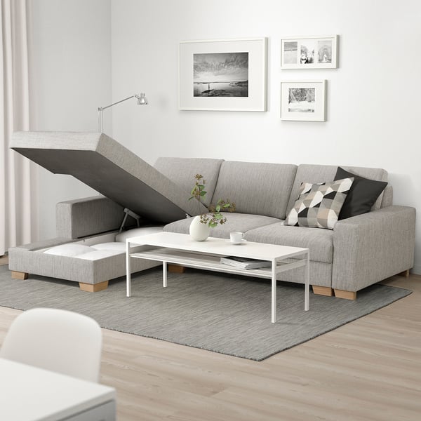 Modernes minimalistisches Sofa mit Stauraum-Chaiselongue. Weißer Couchtisch, Schwarz-Weiß-Dekor, Pflanzen, Bücher und Kunstwerke.