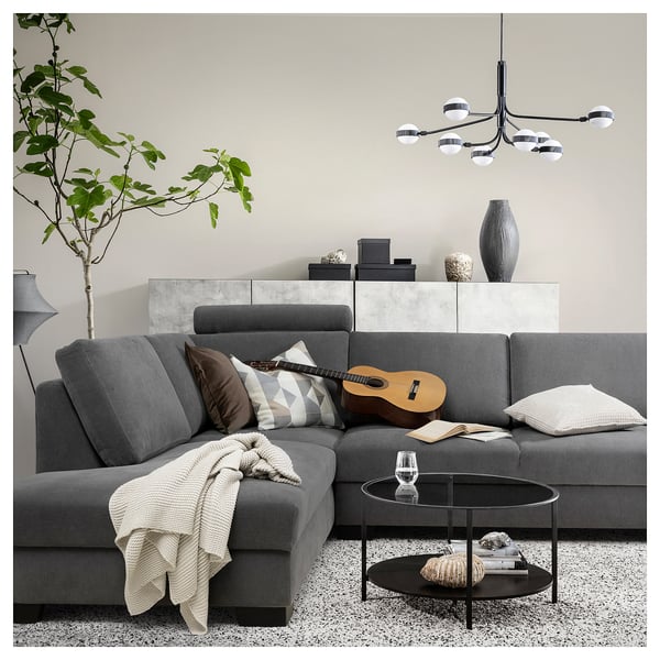 Modernes Wohnzimmer mit grauem SÖRVALLEN-Sofa, Couchtisch, Pflanze und Kronleuchter.