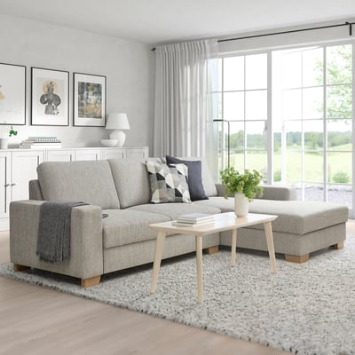 Graues SÖRVALLEN-Sofa mit Holzakzenten, Kissen und Couchtisch. Helles Fenster schafft einen warmen Wohnraum.