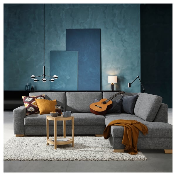 Modernes graues Sofa mit blauen Wänden, Beistelltisch aus Holz und Gitarre, gemütliches Design, graue Kissen.