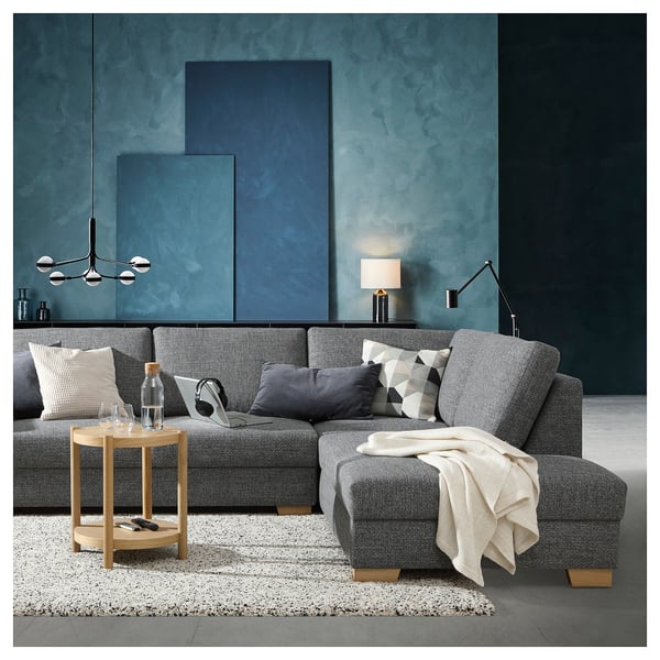 Modernes Wohnzimmer mit grauem SÖRVALLEN-Sofa, Beistelltisch aus Holz, blauer strukturierter Wand und Hängelampe.