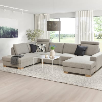 Modernes graues SÖRVALLEN-Sofa mit schwarzen Kissen, großem weißen Teppich und breiten Fenstern.