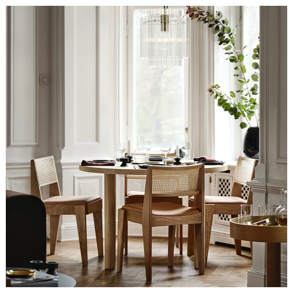 Elegantes Esszimmer mit Holz- und Lederstühlen, rundem Tisch und Kronleuchter. Die Stühle passen perfekt unter den Tisch und unterstreichen das minimalistische Design.