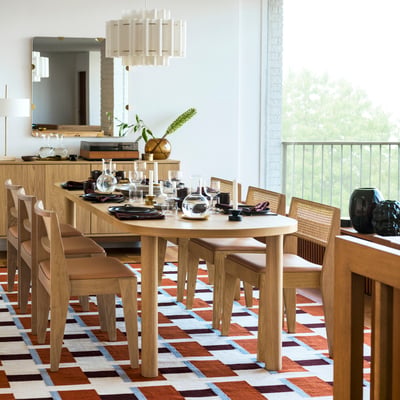 Modernes Esszimmer mit großem Tisch, Ledersesseln, Sideboard aus Holz und Dekorationen.