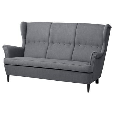Ein graues IKEA STRANDMON 3-Sitzer-Sofa mit hohen, geflügelten Rückenlehnen, geknöpften Kissen und dunklen Holzbeinen.