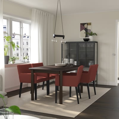 Modernes Esszimmer mit STRANDTORP-Tisch, roten Stühlen und Schrank. Sitzplätze für bis zu 8 Personen. Dunkles Holz, Metallsockel, minimalistisches Dekor.