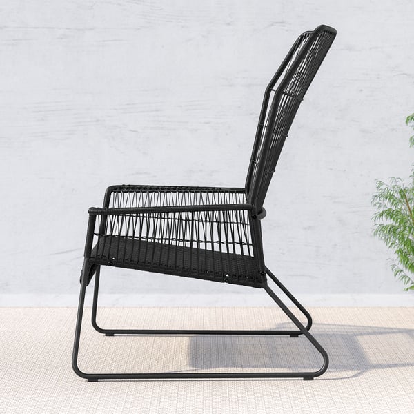 Schwarzer Outdoor-Stuhl aus Korbgeflecht mit geschwungener Rückenlehne und Sitzfläche, vor einer hellen Wand. Minimalistisches Design, bequem zum Entspannen.