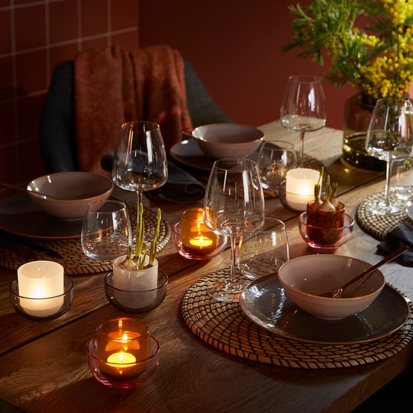 Elegantes Esszimmer mit TALLTITA Teelichthaltern aus Glas in warmen Farben. Kerzen, Schalen und Vasen auf einem Holztisch sorgen für ein gemütliches Ambiente.