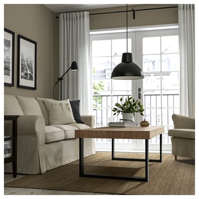 Modernes Wohnzimmer mit beigem Sofa, Couchtisch, Stehlampe und Zugang zum Balkon. Großes Fenster, Vorhänge und Pflanzendekoration.