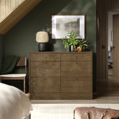 Modernes Schlafzimmer mit Schubladen aus TONSTAD-Eiche, weißer Lampe, grüner Wand, großem Foto, Pflanze und Stuhl.