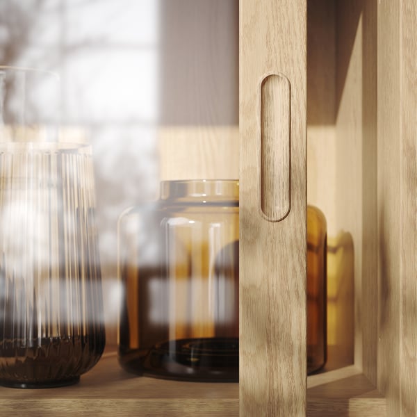 Moderner Holzschrank mit schlankem Eichengriff, in dem Glasvasen ausgestellt sind – handwerkliche Qualität ist offensichtlich.