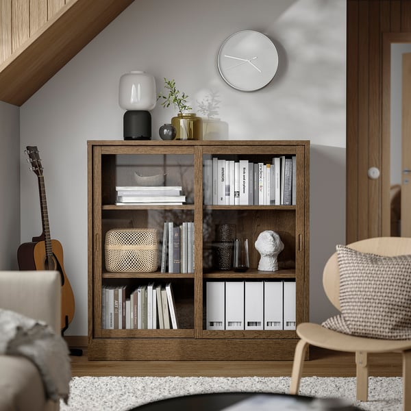 TONSTAD Bücherregal aus Holz mit Glastüren, Büchern, Dekor, Uhr, Gitarre.