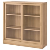 Ein TONSTAD Holzschrank in Eichenfarbe. Es sind Glasschiebetüren, drei Regale und ein klassisches Design.