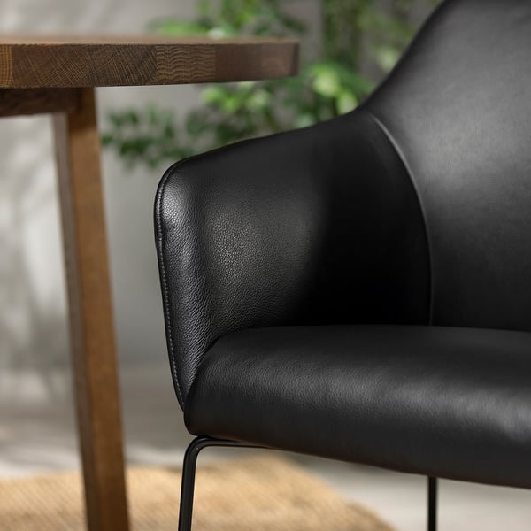 Nahaufnahme eines luxuriösen schwarzen Ledersessels mit schlankem Design und Metallrahmen, gepolstert für Komfort.
