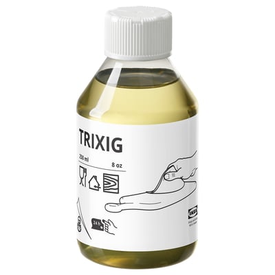 Eine weiße Flasche TRIXIG Pflanzenöl mit einer gelblichen Flüssigkeit im Inneren, auf deren Etikett Musiknoten stehen.