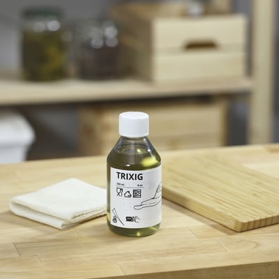Grüne TRIXIG Flasche auf Holztisch mit Tuch und Brett.
