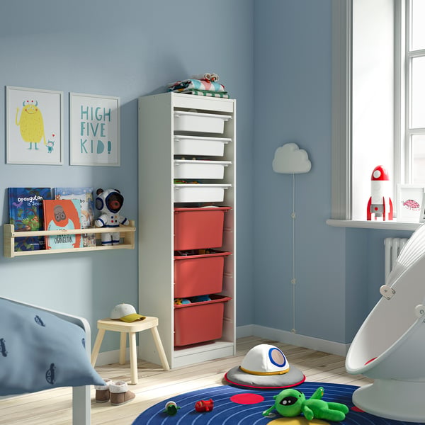 Kinderzimmer mit TROFAST hellblauem Stauraum aus Spanplatten und Kunststoff. Er ist gefüllt mit roten Gitterboxen, kleiner als ein hohes Fenster in der Nähe.
