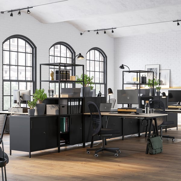 Moderner doppelseitiger Büroschrank in Schwarz mit Regalen, Schubladen und Schiebetüren. Erhellt durch große Bogenfenster.
