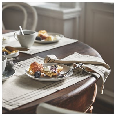 Gemütliches Frühstück mit Scone, Kaffee und Gebäck auf beiger Matte.