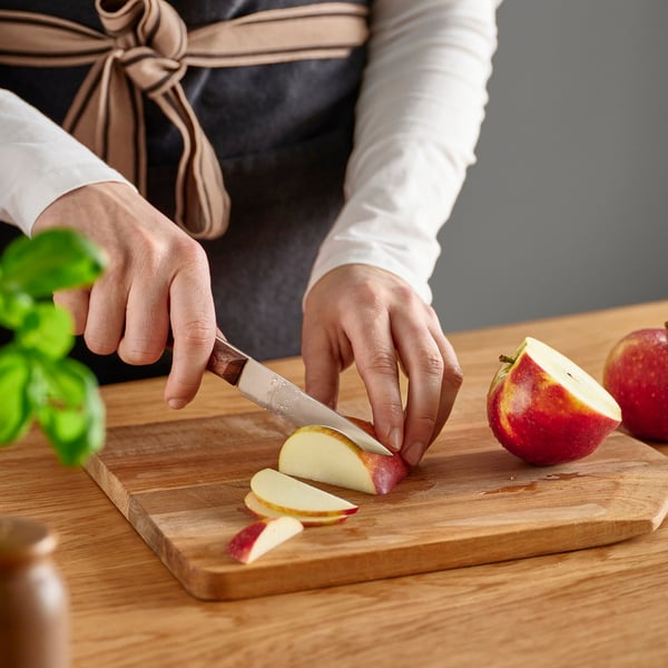 Person schneidet Apfel auf Holzschneidebrett mit VARDAGEN-Messer.