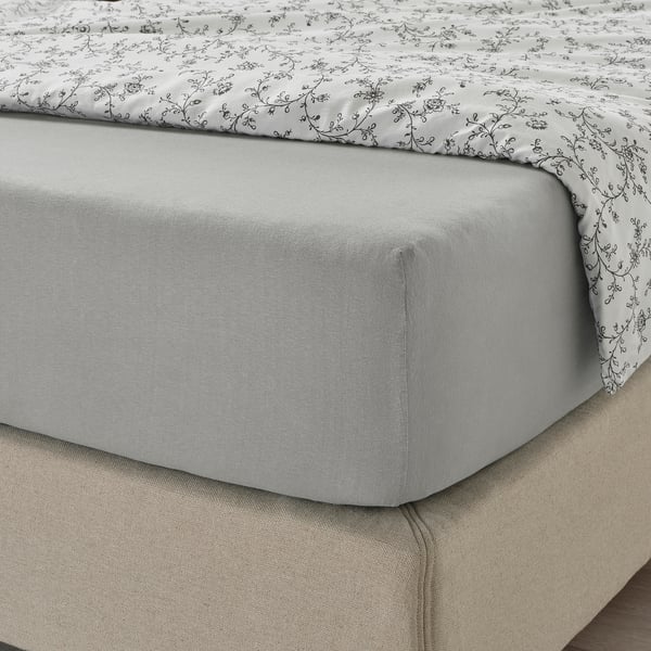 Graues Spannbettlaken mit Blumendruck, perfekt gespannt auf der Matratze.