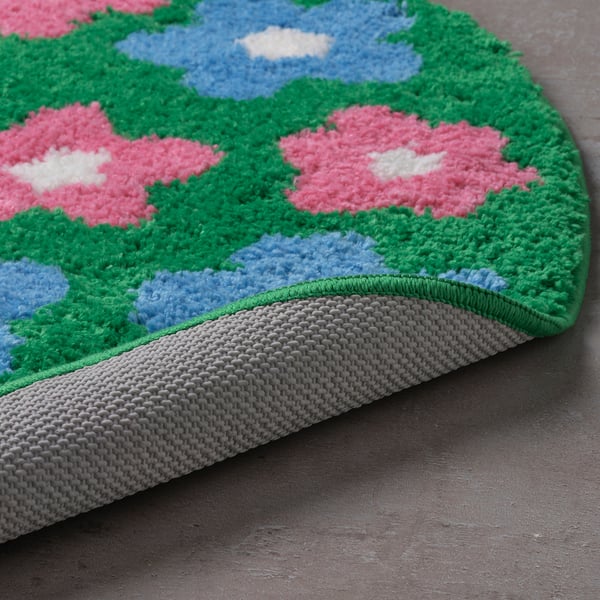 Badematte mit rosa Blumen, grünen Blättern und blauem Himmel. Weicher, dicker Flor für mehr Komfort. Rutschfeste graue Unterseite.