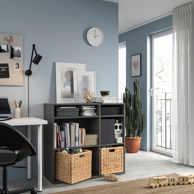 Modernes blaues Home Office mit dunkelgrauer Aufbewahrungseinheit von VIHALS, weißem Schreibtisch, schwarzem Stuhl, Wanduhr und großem Fenster mit weißen Vorhängen.